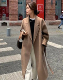 Women's 100% wool belted long warp-knit coat with double-breasted lapel and loose fit, featuring a refined texture and waist-cinching belt for office wear or city streets.