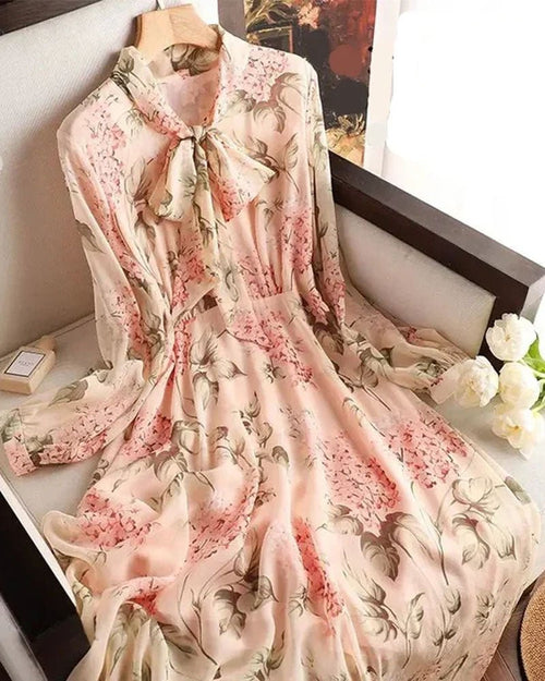 Woman posing in the Floral-Print Chiffon Bow-Neck Long-Sleeve Dress, airy 100 % polyester chiffon and self-tie bow collar give romantic 70s vibes—your breathable 70-85 °F spring-to-summer statement.