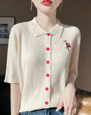 Short-sleeved women's knitted cardigan made from soft worsted wool. Features a classic polo collar and a vibrant embroidered flamingo design with delicate bead accents.