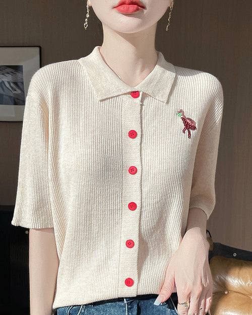 Short-sleeved women's knitted cardigan made from soft worsted wool. Features a classic polo collar and a vibrant embroidered flamingo design with delicate bead accents.