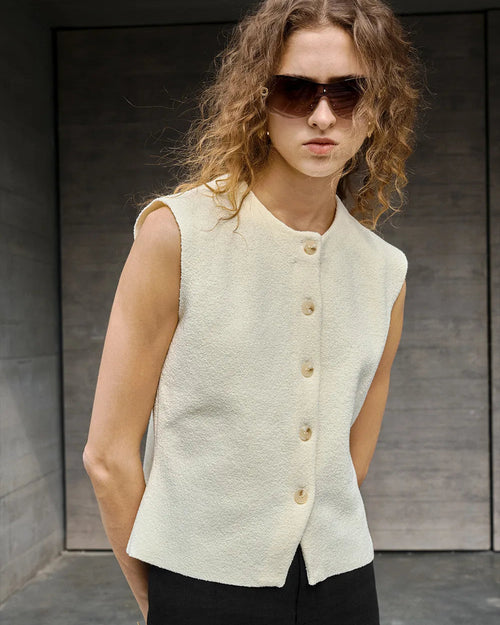A retro-inspired sleeveless vest featuring a classic round neck and button-front closure. This lightweight top offers a vintage aesthetic and relaxed fit, perfect for layering over tees or wearing alone in warm weather.