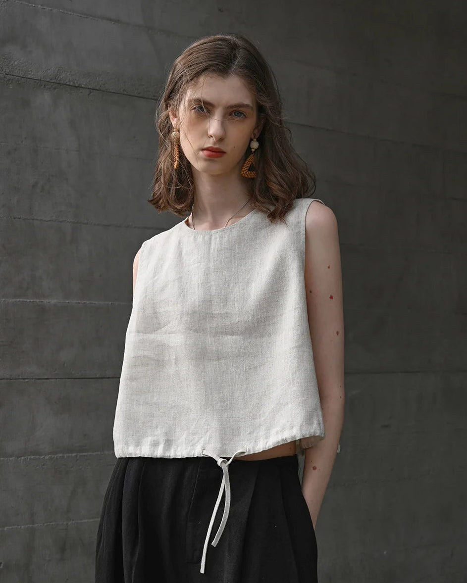 A breathable linen cropped vest featuring a classic crew neck and adjustable drawstring. This lightweight summer top offers a relaxed fit and airy texture, perfect for staying cool in warm weather.