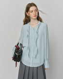 A slim-fit chiffon blouse featuring an asymmetric flounce V-neckline. Lightweight, slightly stretchy, and effortlessly elegant. 