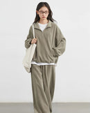 Women's green granular velvet stand-collar zip top and pleated wide-leg pants set, featuring opaque soft texture and loose fit for sporty office wear or autumn layering.