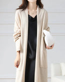 Woman city-strolling in an open-front 100 % Merino-wool long cardigan, 19.5 micron superfine knit drapes like jersey—your cozy yet breathable 45-65 °F fall-to-spring layer.