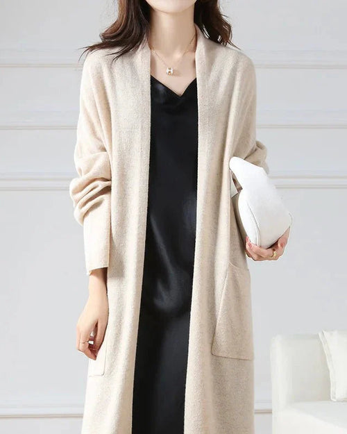 Woman city-strolling in an open-front 100 % Merino-wool long cardigan, 19.5 micron superfine knit drapes like jersey—your cozy yet breathable 45-65 °F fall-to-spring layer.