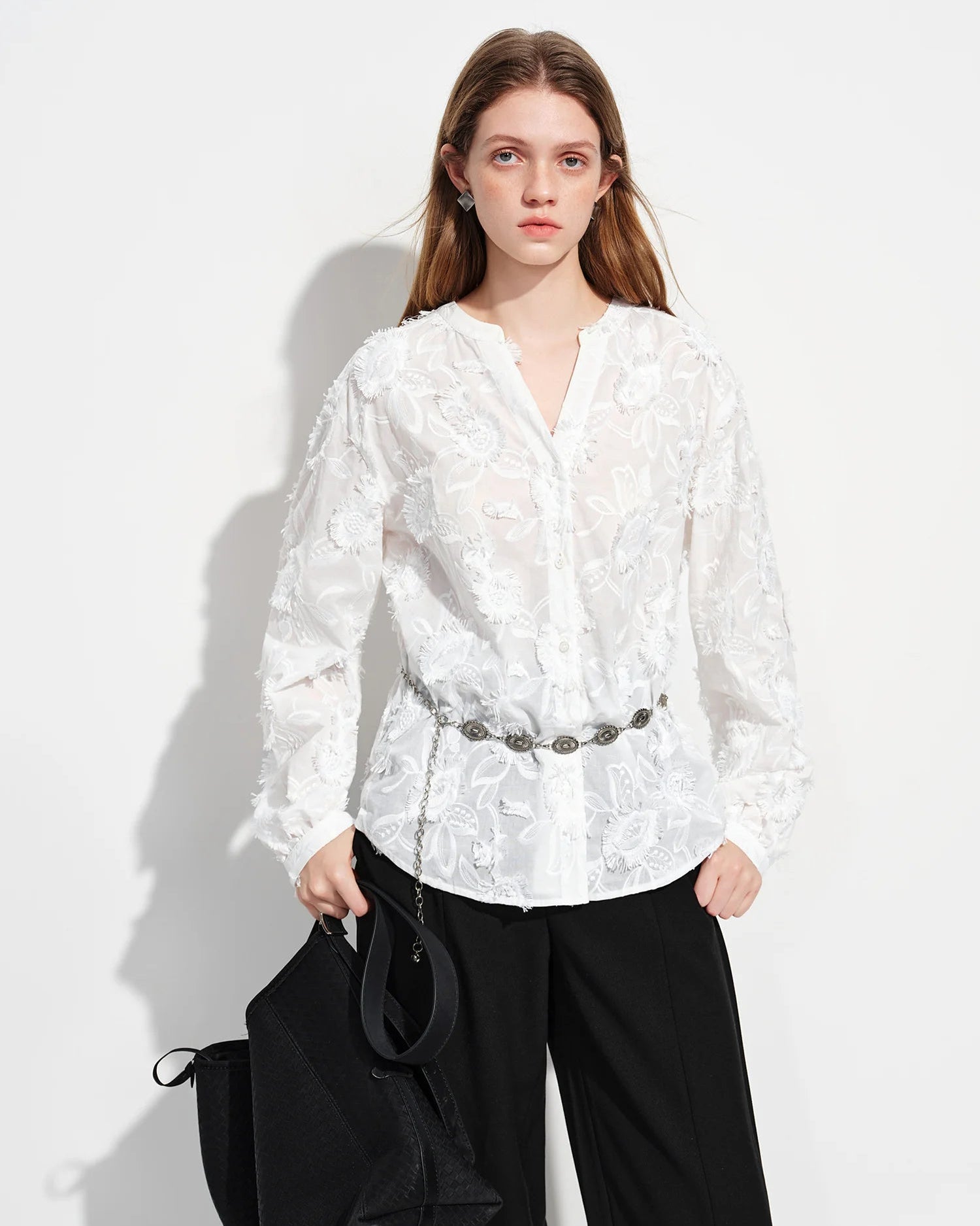 The jacquard knit construction lends a quiet tactile richness, while the V-neckline and full-length sleeves create a polished.